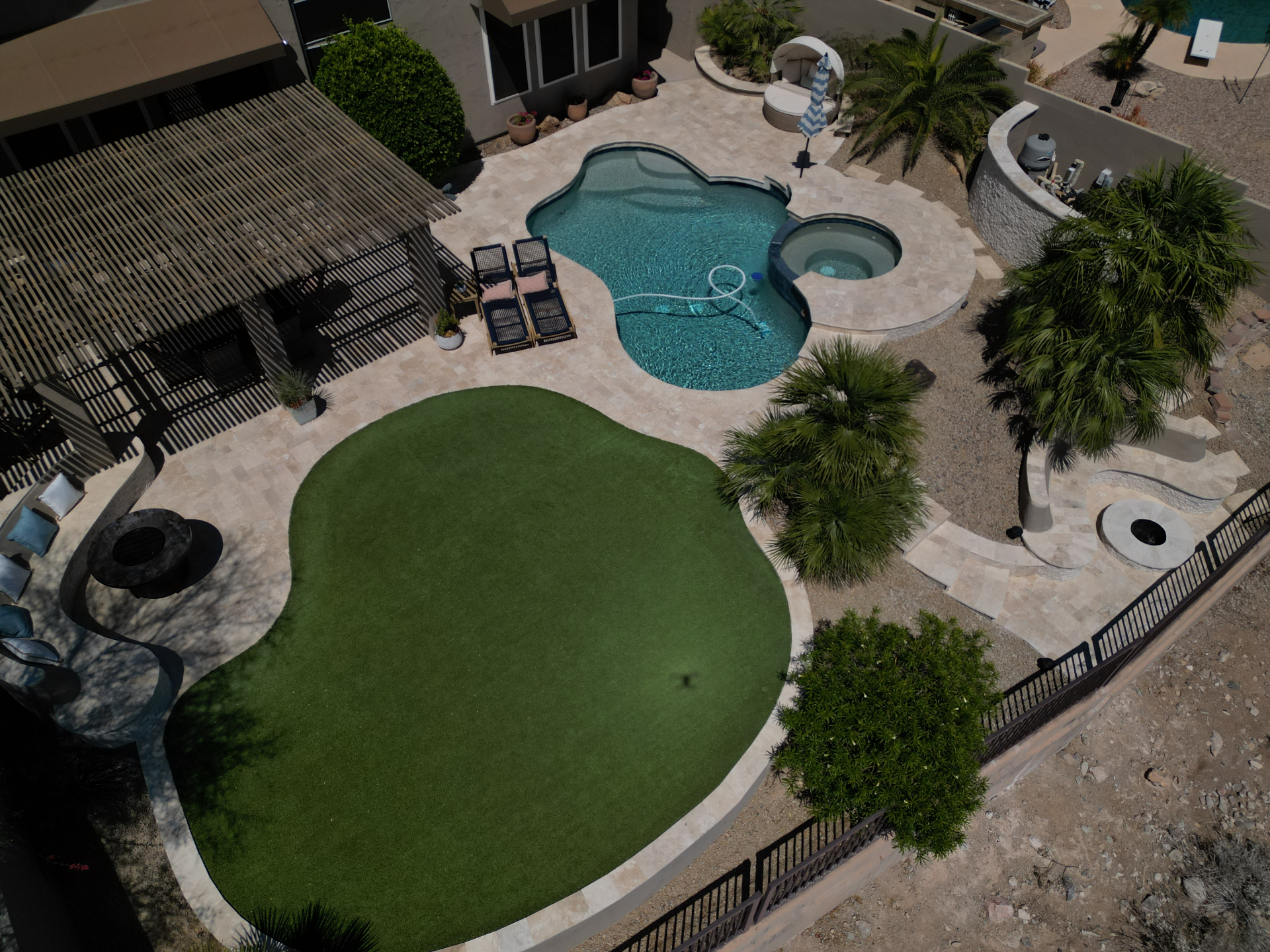 Aerial view of a luxury Arizona backyard with travertine pool deck, spa, pergola, fire pit and lawn